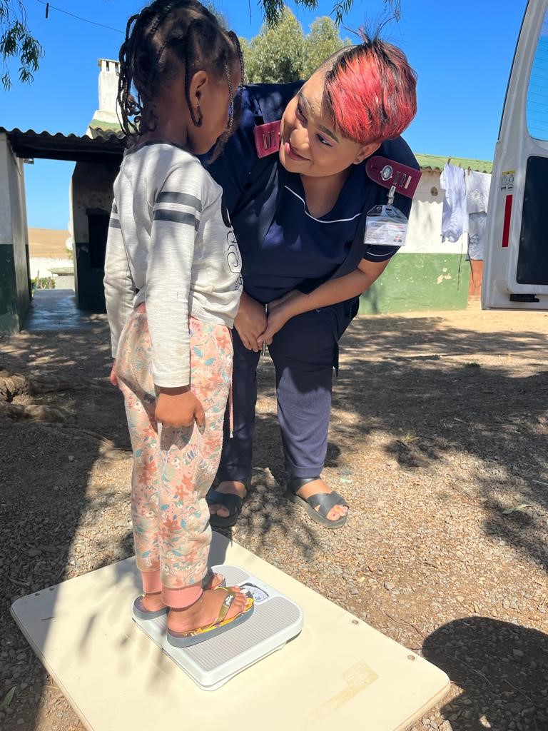 Sr Tamlin Sibole weighs three-year-old Shakiela Louw, daughter of Simonè Louw, during her check-up.