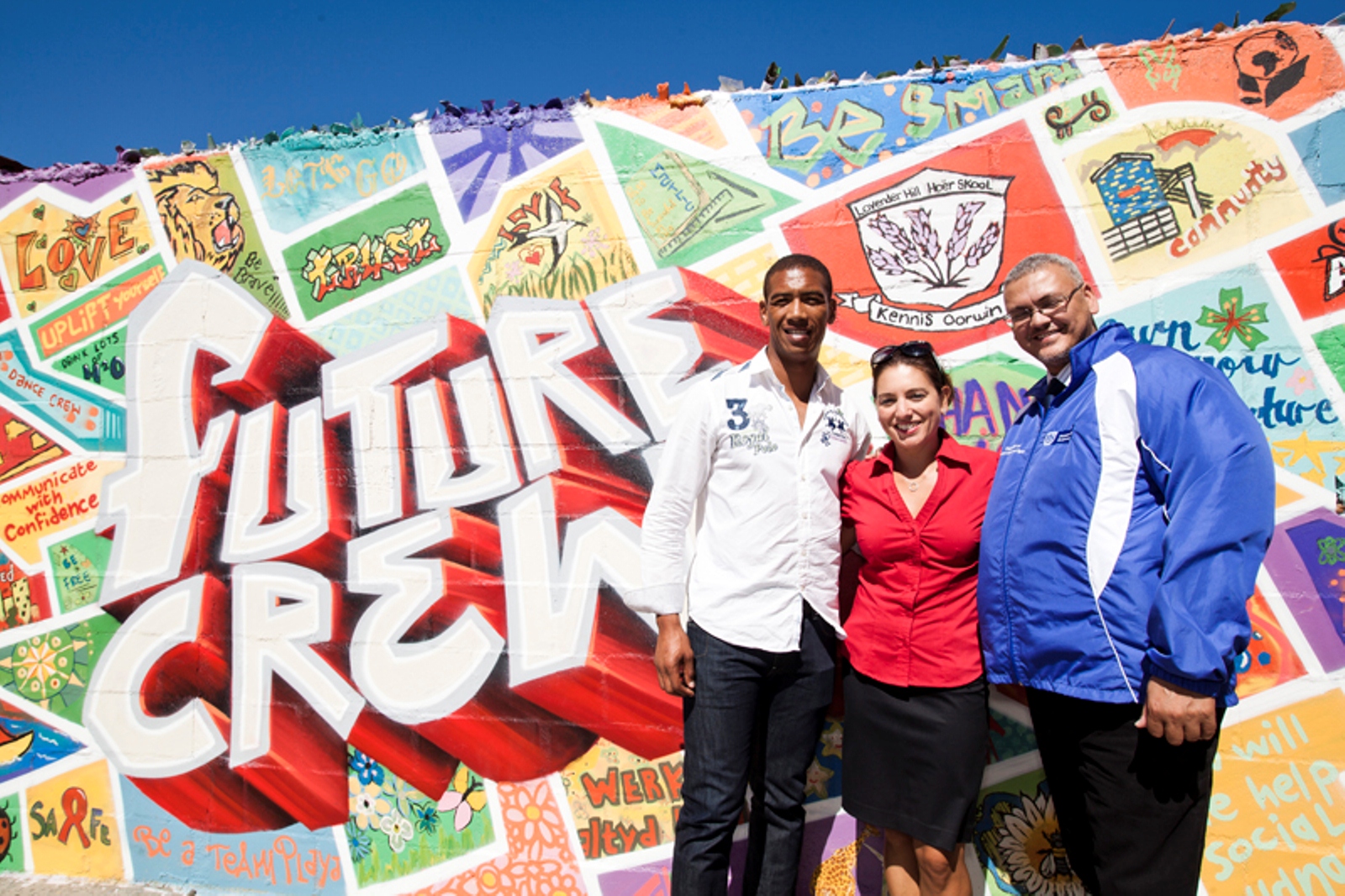 Ashwin Willemse, Theresa Kearly (Virgin Active) and Adv Lyndon Bouah (Department of Cultural Affairs and Sport) in front of the FUTURE CREW mural, which was unveiled at the school.