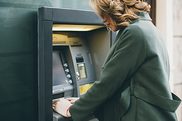 A lady using the ATM to withdraw cash.