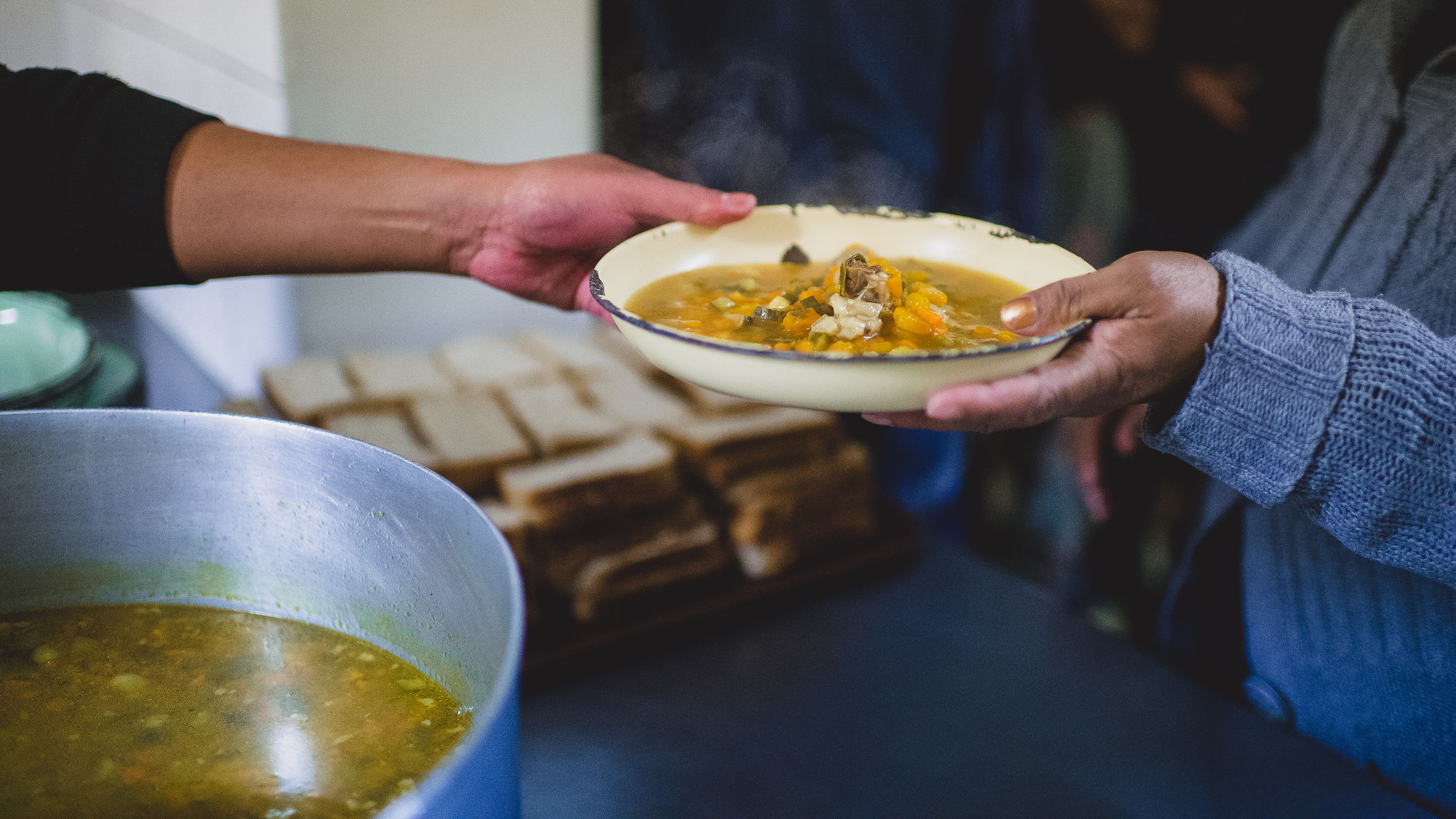 Passing a plate of food with stew soup and bread to the homeless