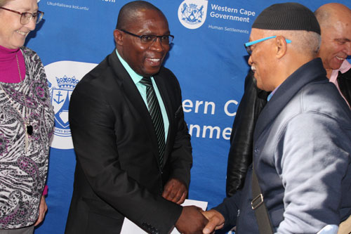 Minister Bonginkosi Madikizela hands over a senior beneficiary's title deed