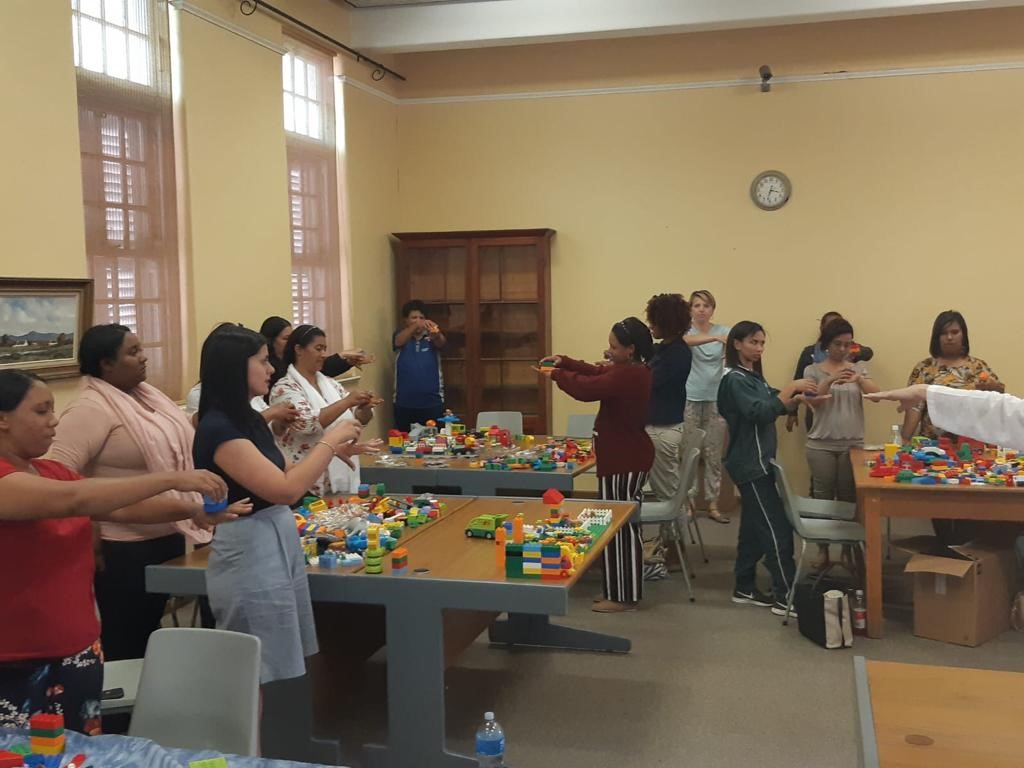 Ladies standing around tables working with plastic building blocks