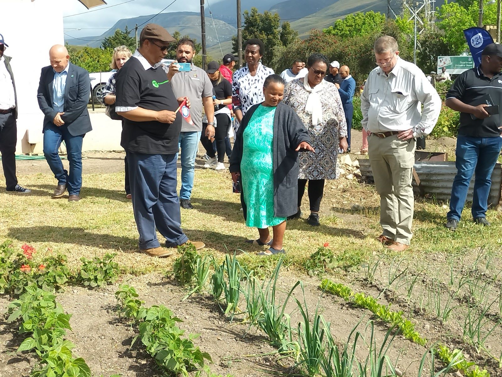 Local resident Sarah Brand shows minister Meyer her food garden