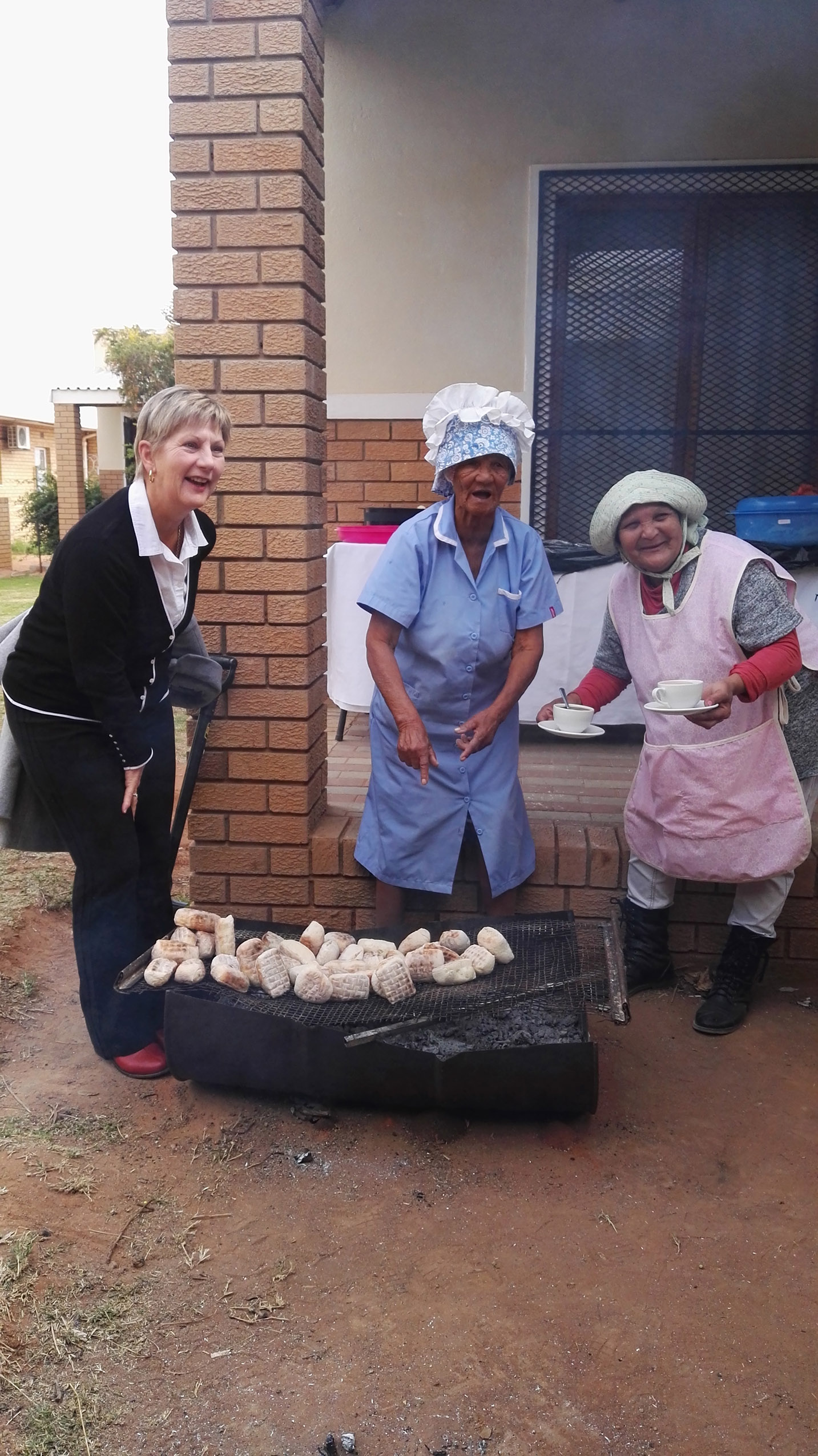 Minister Marais with two locals enjoying griddlecake (roosterkoek)