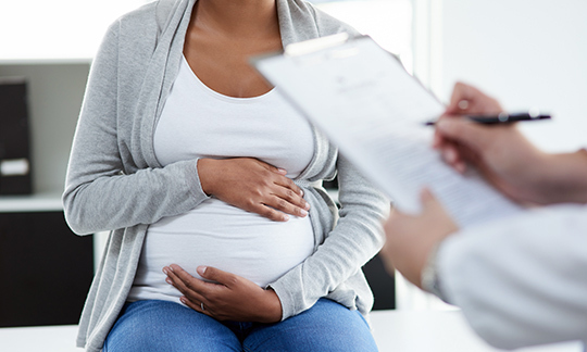 A pregnant woman visiting the doctor holding her tummy