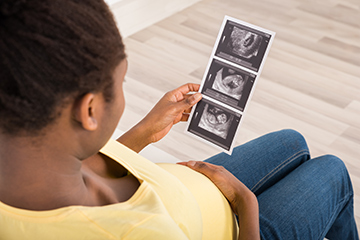 Pregnant woman holding a copy of her ultra sound scan