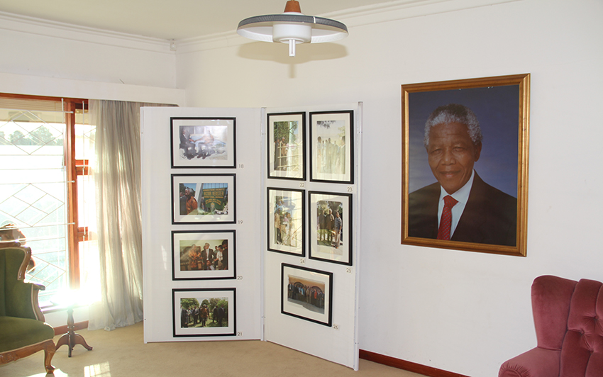 Some photos from the exhibit are seen next to a portrait of president Mandela in the lounge of the house