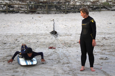 9Miles facilitator, Nathaniel Stemmet, teaching Minister Marais the basics of surfing.
