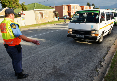 A provincial traffic official inspects the roadworthiness of a minibus taxi at the school. 