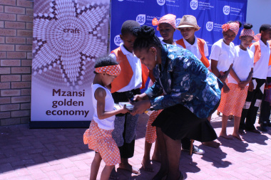 DCAS Minister Mbombo handing  promotional material to learners from Koelenhof Primary school who entertained guest at the launch