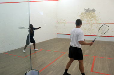 Eager players alternate in striking the ball at the squash court