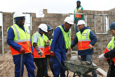 Minister Bonginkosi Madikizela (left) and Western Cape Human Settlements Head of Department Thando Mguli (pushing the wheelbarrow) hard at work at Pelican Park.