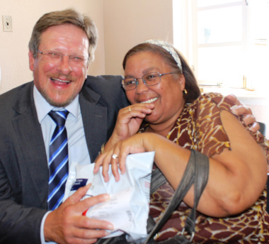 The Western Cape Minister of Health, Mr Theuns Botha, with a patient from Belgravia receiving her medication parcel.