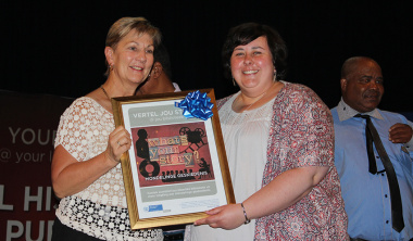 Minister Anroux Marais hands over a framed Oral History Initiative poster to Suzanne Vermeulen from Hartenbosch public library.