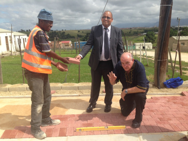 Minister Robin Carlisle, Mayor Standers and a construction worker stand on site in Thembalethu