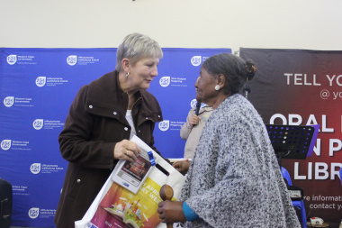 A local storyteller receives the Oral History DVD from Minister Marais in the Community Hall in Mamre