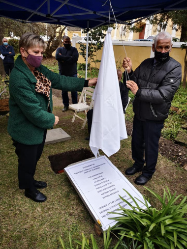 Minister Marias and Dr Isaac Balie unveil the plaque to memorialize the burial of Michael Balie at the Genadendal Mission Museum as the community looks on.