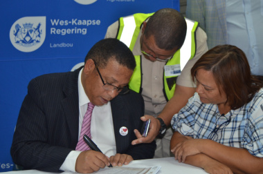 Assisted by Neil Zimri of the Department of Agriculture, Minister Meyer registers grain farmer, Alfreda Mars, who farms in  the Swartland District