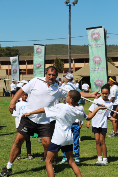 One of the youth being showed how to throw a javelin