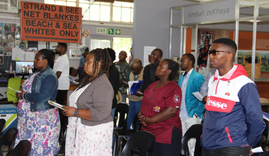 Participants stand to sing Nkosi Sikelel' iAfrika at the start of the Nation Building and Social Cohesion Community Conversations event at the Lwandle Migrant Museum