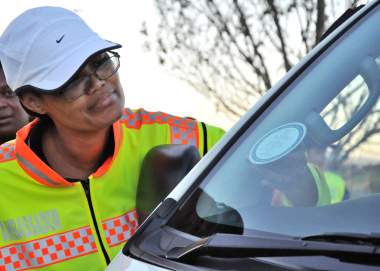 Road safety officer Lizel Plaatjies puts a sticker on a vehicle.
