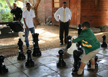 Ryan Daniels makes a move on the giant chess board, while Kenny Solomon and Dr Ivan Meyer look on.