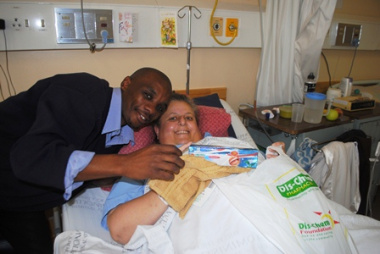 Mr Jemes Rwayi from Dis-Chem Foundation hands a gift bag of toiletries to Ms Denise Knight.