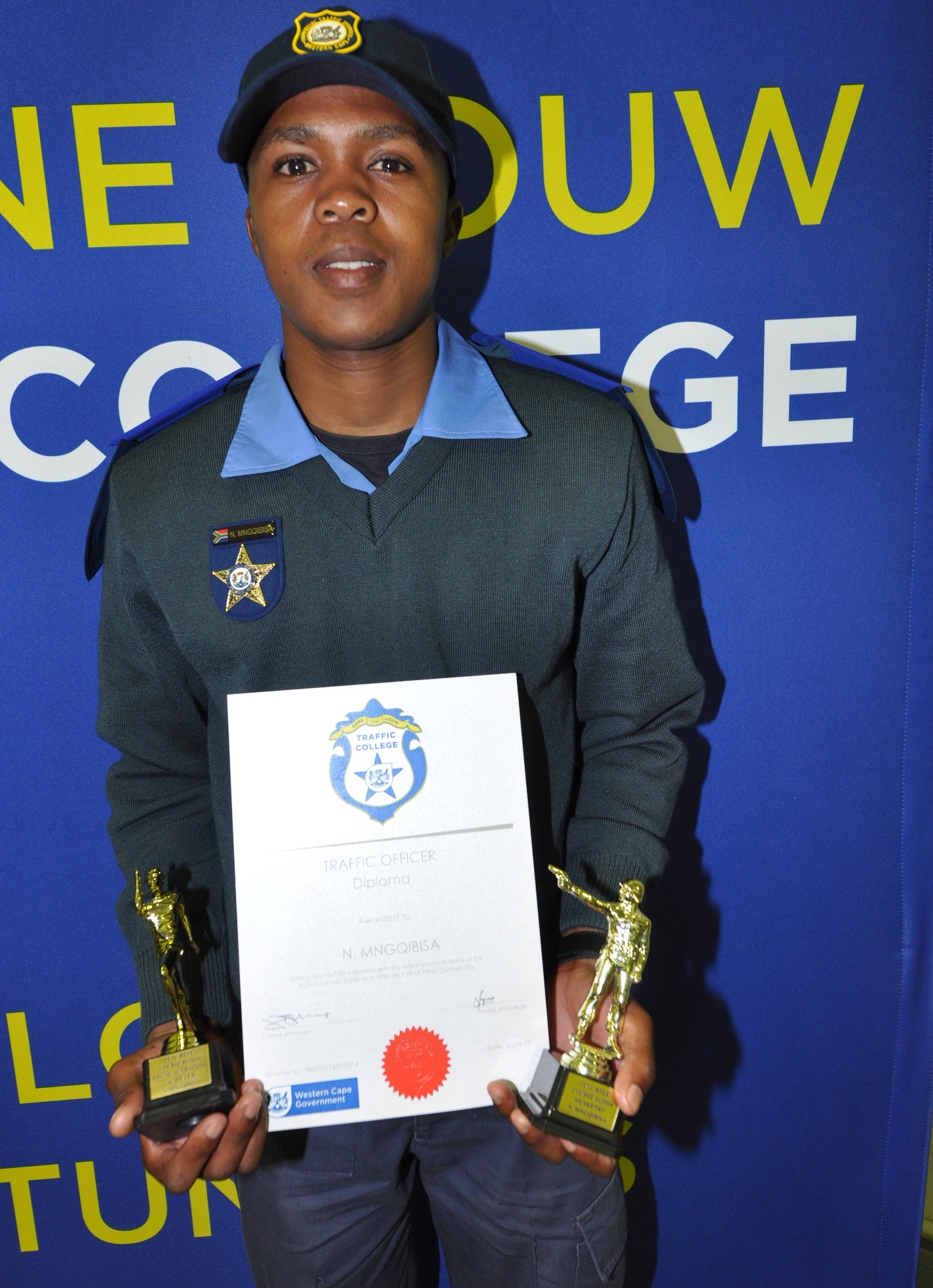 Traffic Officer Nande Mnqgibisa with his traffic diploma and two trophies.