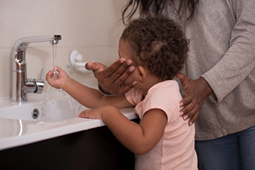 Mother helping child washing her hands. 