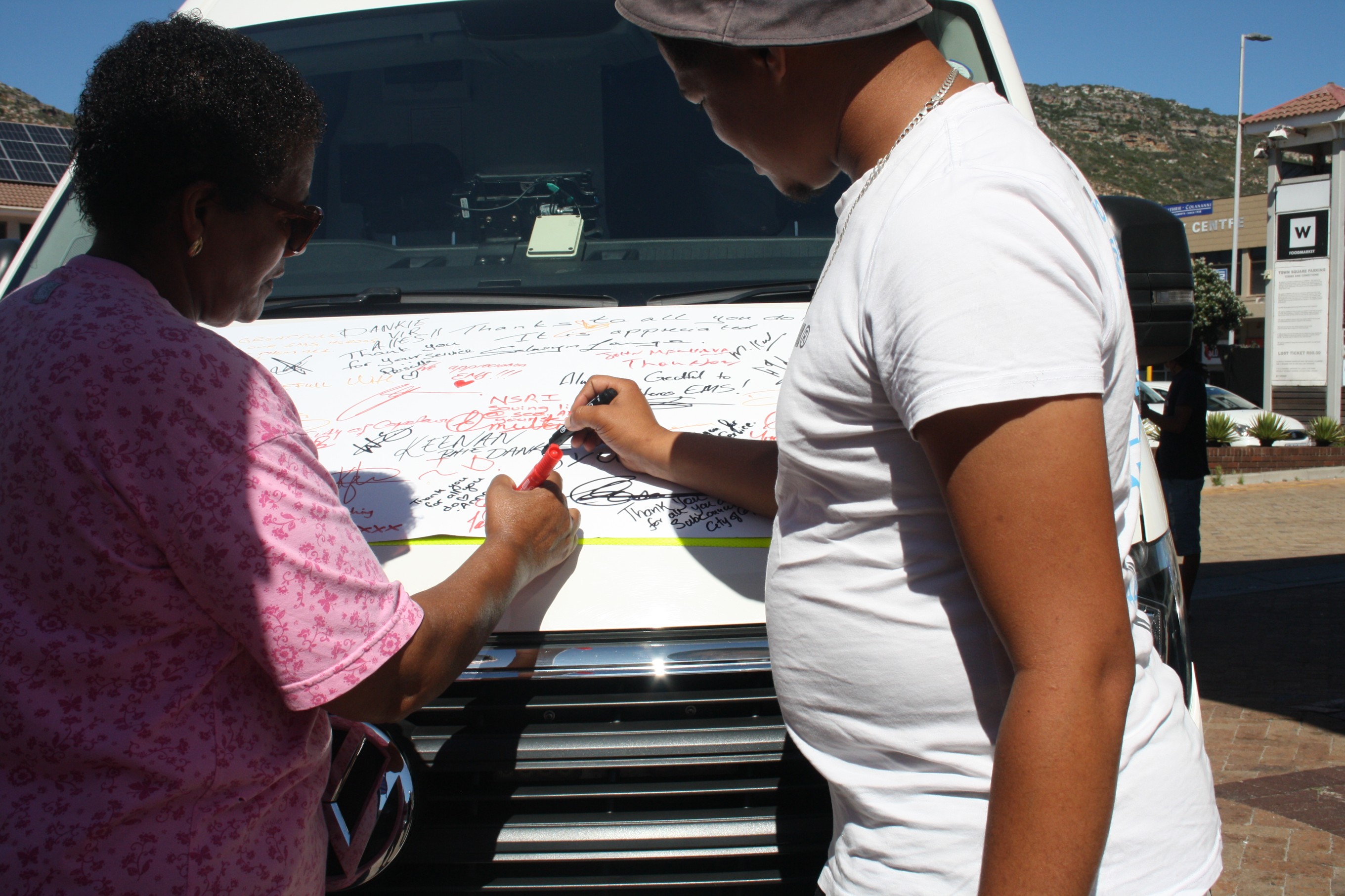 Two residents write messages for EMS personnel in Fish Hoek.