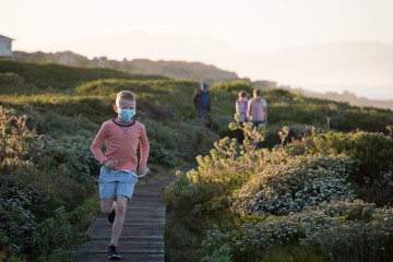 A young boy with mask on taking a walk with his family